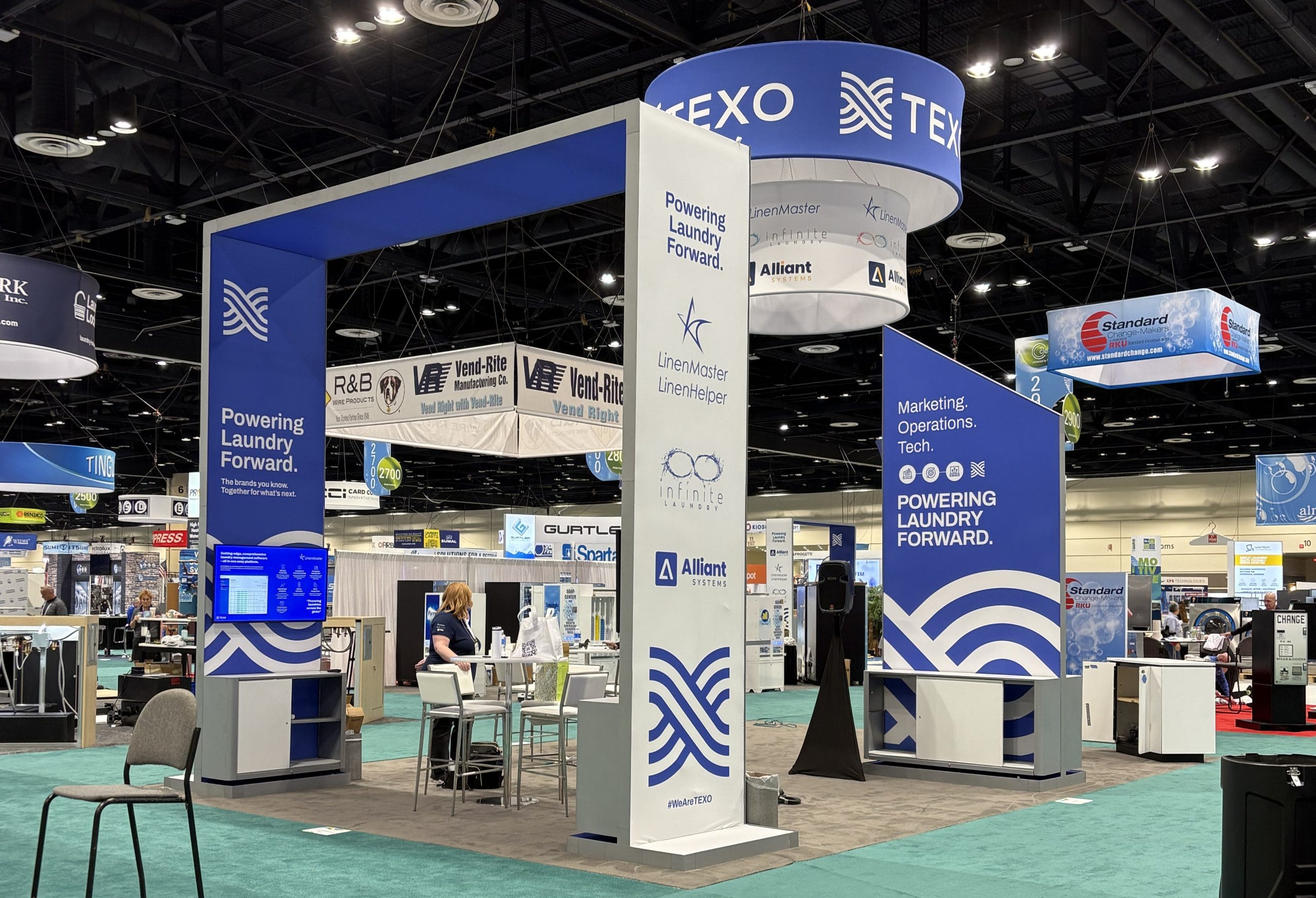Custom trade show island exhibit with fabric towers and an overhead hanging sign